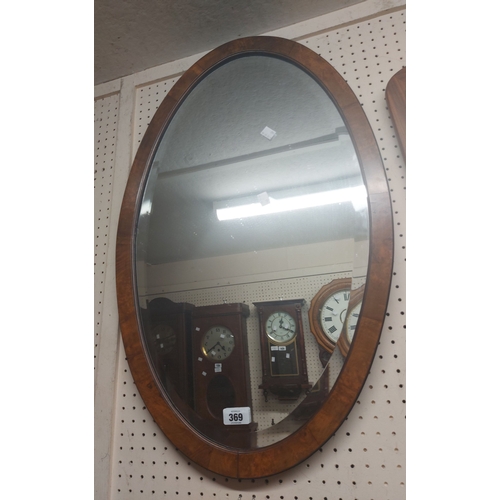 369 - An Edwardian walnut framed bevelled oval wall mirror