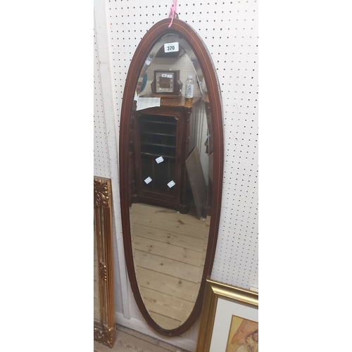 370 - An Edwardian mahogany and strung framed narrow bevelled oval wall mirror