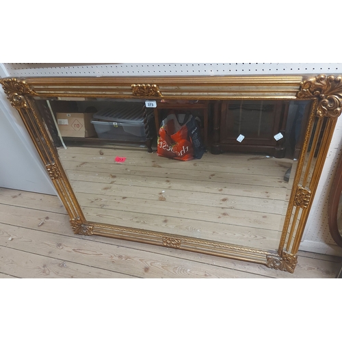 373 - A large reproduction gilt framed bevelled oblong wall mirror with ornate border