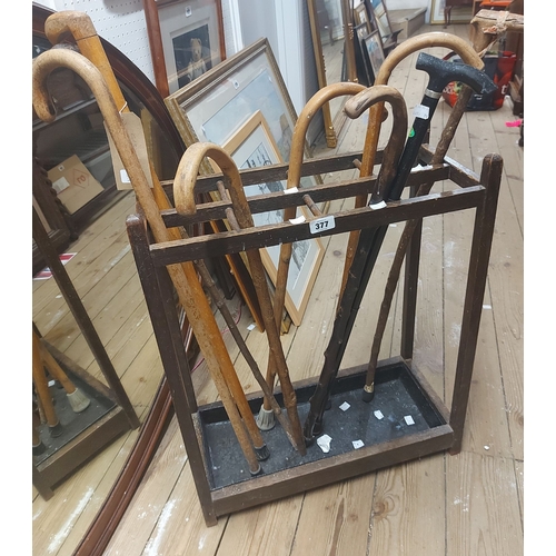 377 - A 57cm old oak stick stand with iron drip tray - sold with nine assorted walking sticks