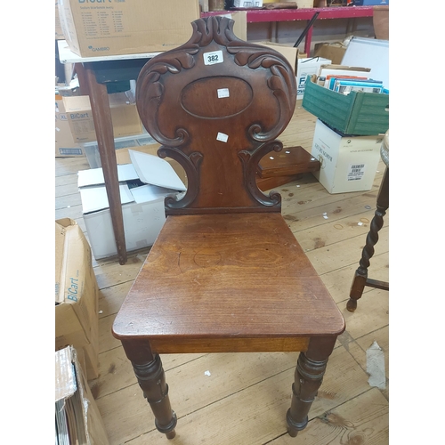 382 - A Victorian mahogany hall chair with carved decoration and solid seat panel, set on turned front leg... 