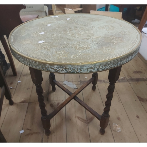 384 - A 60cm diameter Indian brass clad tray topped tea table, set on a folding barley twist base