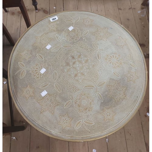 384 - A 60cm diameter Indian brass clad tray topped tea table, set on a folding barley twist base
