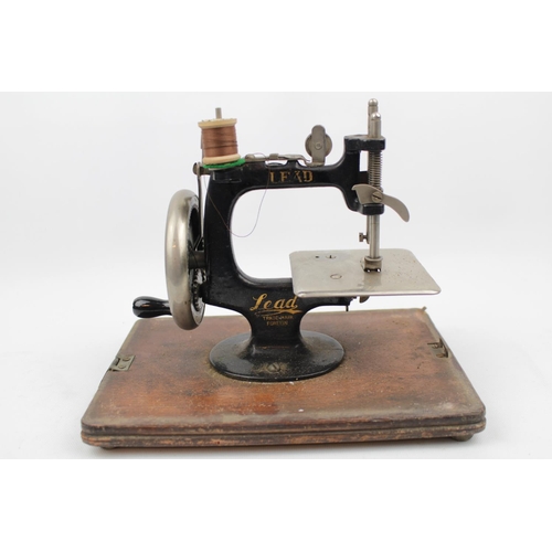 236 - Lead Machine German Childs sewing machine in Walnut domed case