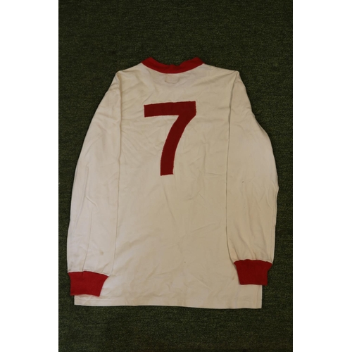 GEORGE BEST 1960's MATCH WORN MANCHESTER UNITED JERSEY

George Best was football’s version of The Beatles. The first true celebrity footballer, Best possessed an incredible ability to dribble the football and a lifestyle to match. To this day, Best is considered one of the absolute best to ever lace up their boots. Best famously led Manchester United to European Cup glory in 1968, the same season he won the Ballon d’Or as the best European Footballer. An exact date for this garment is difficult to discern, but it is believed to date to the early 1960’s of Best's career. This garment was an original squad equipment at Old Trafford, and was worn on the pitch by George Best. George originally gifted the uniform to a fellow player when he moved to America to play in the NASL.

The jersey is white with with red collar and long sleeve cuffs, #7 is sewn on back in red fabric too. Correct Umbro label is sewn in the collar and another Umbro print is evident on the lower hem.

The jersey is accompanied by a letter of authenticity which states that the vendor got this jersey in 2009 from the collection of the Irish player and Best's teammate Shay Brennan's family