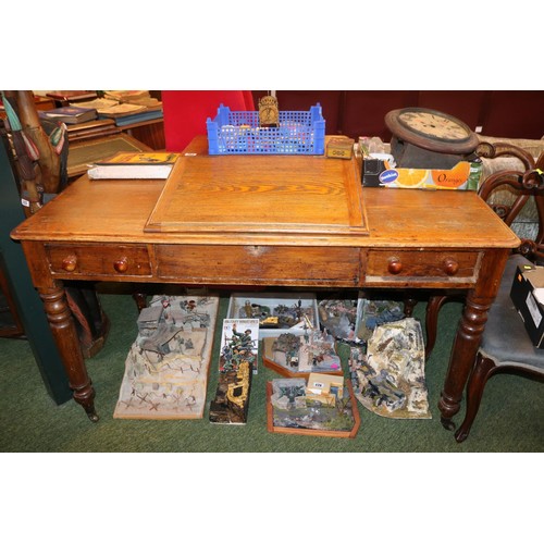 383 - Large Oak sloped top desk with turned handles supported on turned legs and casters