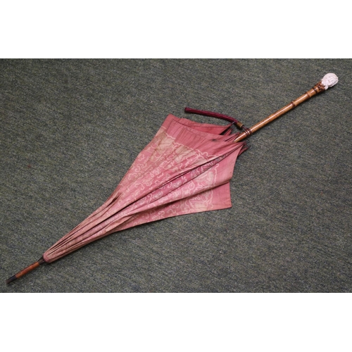 135 - A Vintage Kendall parasol, with White and Maroon floral decoration, the carved bone handle formed as... 