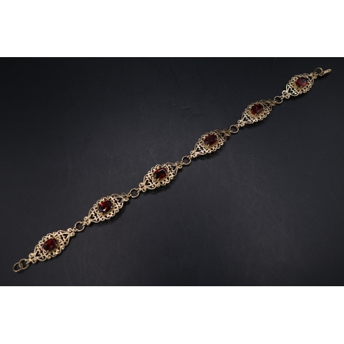 Ladies 9ct Gold Garnet set bracelet of pierced scroll design. 8.1g total weight