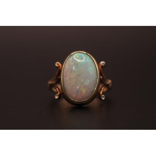 186 - Ladies 9ct Gold Oval Opal ring, set with Opal measuring 16mm x 11mm within rub over setting and fleu... 