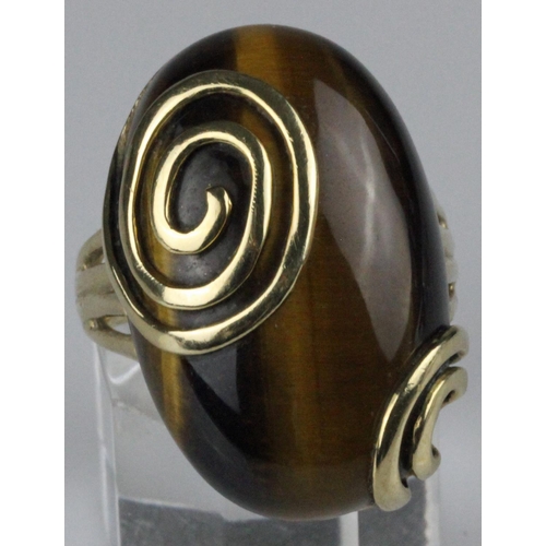 221 - 9ct gold dress ring, set with a large oval cabochon tigers eye stone, measuring approximately 28mm x... 