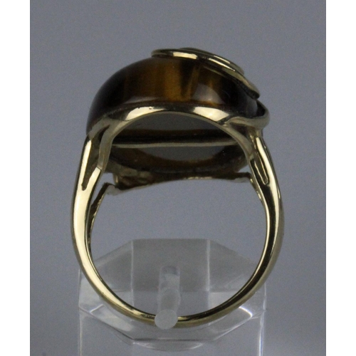 221 - 9ct gold dress ring, set with a large oval cabochon tigers eye stone, measuring approximately 28mm x... 