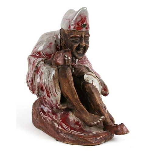 443 - A Chinese Shiwan pottery figure in the form of an emaciated robed figure holding his shoe, impressed... 
