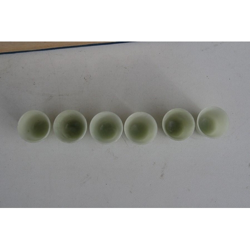 328 - A cased set of twelve Chinese jade like cups with D & S Howlett collection label to the undersid... 