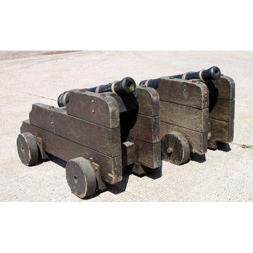 294 - A pair of 19th century solid oak Cannon carriages on oak wheels (slightly modified to hold two ornam... 