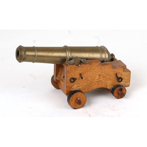 353 - A desk top cannon with a brass barrel mounted on a wooden carriage with metal fittings, seated on a ... 