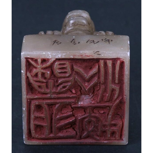 554 - A Chinese carved stone desk seal surmounted a crouching kylin. 5cm (2 ins) high