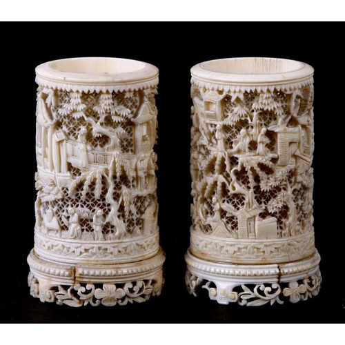 556 - A pair of late 19th century Chinese finely pierced ivory vases decorated figures in a garden. 11cm (... 