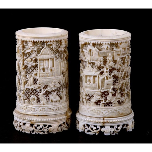 556 - A pair of late 19th century Chinese finely pierced ivory vases decorated figures in a garden. 11cm (... 