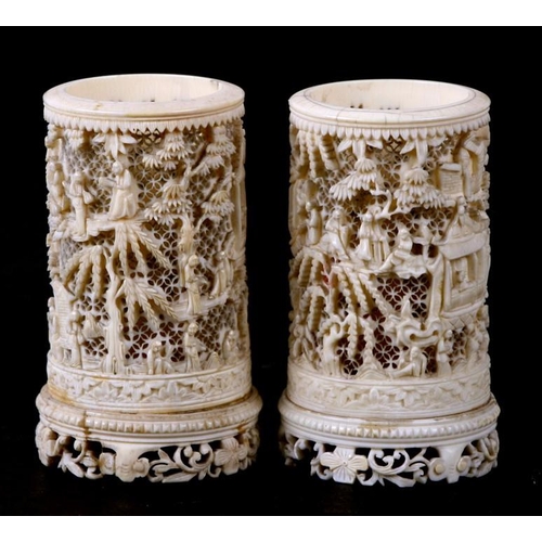 556 - A pair of late 19th century Chinese finely pierced ivory vases decorated figures in a garden. 11cm (... 