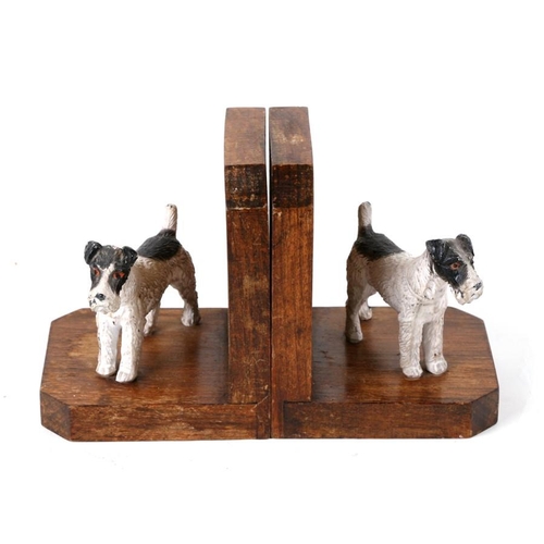 653 - A pair of cold painted spelter and oak bookends in the form of two terrier dogs. 13cm (5 ins) high