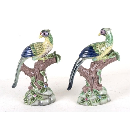 812 - A pair of Chinese style pottery birds perched on tree stumps, 23cms (9ins) high.