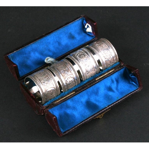 939 - A set of white metal napkin rings with engraved foliate decoration, cased.