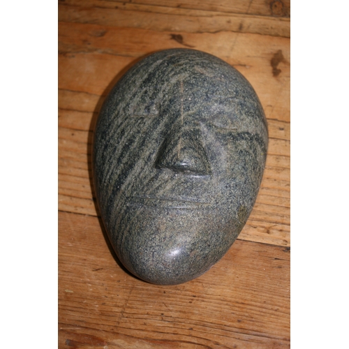 889 - An Inuit mottled green stone carving in the form of a face, 16cms (6.25ins) high.