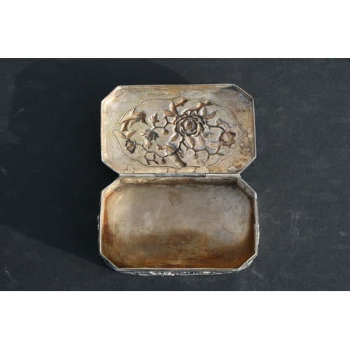 543 - A Chinese silver snuff box of shaped rectangular form with embossed bird, flower and dragon decorati... 