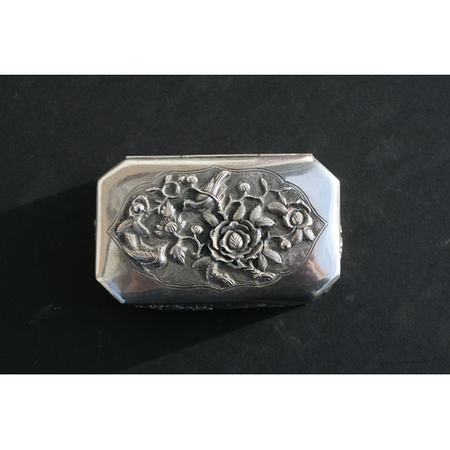 543 - A Chinese silver snuff box of shaped rectangular form with embossed bird, flower and dragon decorati... 