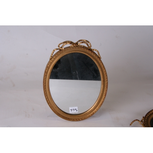 773 - A pair of George III style oval gilt gesso ribbon tie wall mirrors, 23cms (9ins) diameter.