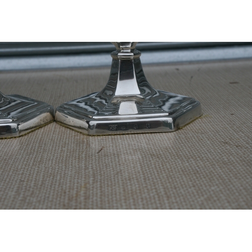 160 - A pair of Edwardian silver candlesticks, each with slender baluster form columns on stepped hexagon ... 