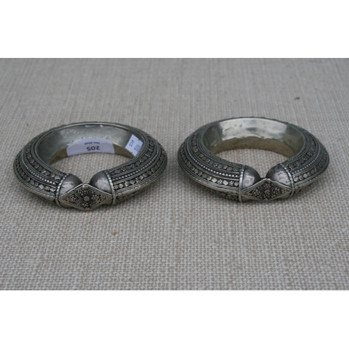 205 - A pair of heavy white metal (tests as silver) and gold tribal bangles, 11.5cms (4.5ins diameter (2).