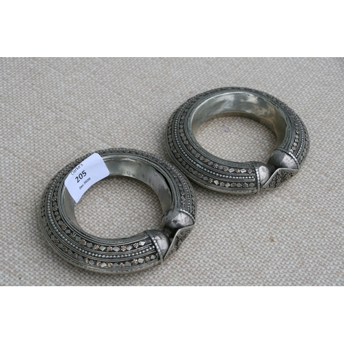 205 - A pair of heavy white metal (tests as silver) and gold tribal bangles, 11.5cms (4.5ins diameter (2).