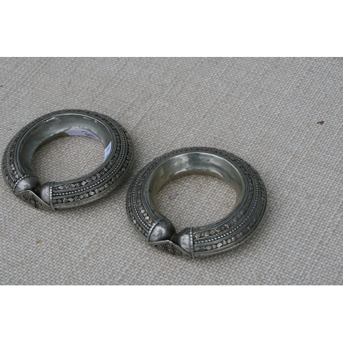 205 - A pair of heavy white metal (tests as silver) and gold tribal bangles, 11.5cms (4.5ins diameter (2).