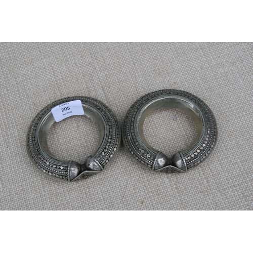 205 - A pair of heavy white metal (tests as silver) and gold tribal bangles, 11.5cms (4.5ins diameter (2).