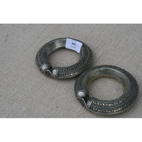 205 - A pair of heavy white metal (tests as silver) and gold tribal bangles, 11.5cms (4.5ins diameter (2).