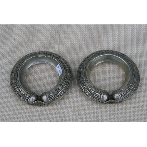 205 - A pair of heavy white metal (tests as silver) and gold tribal bangles, 11.5cms (4.5ins diameter (2).