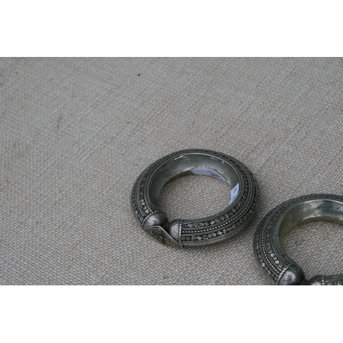 205 - A pair of heavy white metal (tests as silver) and gold tribal bangles, 11.5cms (4.5ins diameter (2).