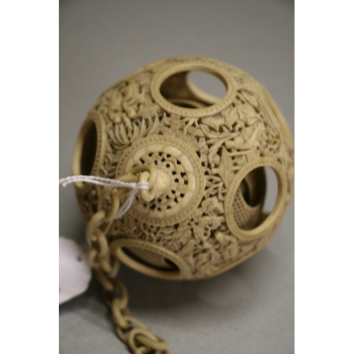 502 - A 19th century Chinese ivory hanging puzzle ball decorated with figures in a landscape, 10cms 94ins)... 