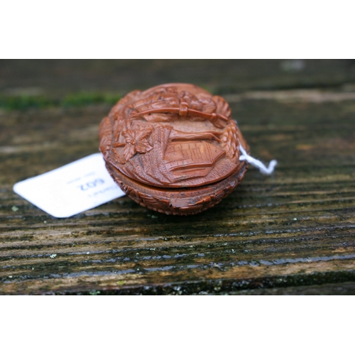 602 - A Georgian coquilla nut snuff box deeply carved with a figural scene depicting a woman holding a bab... 