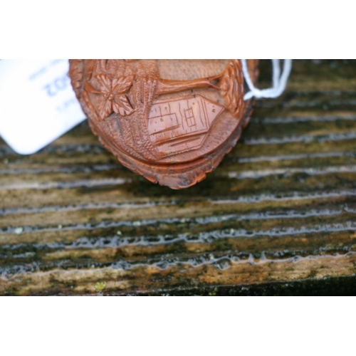 602 - A Georgian coquilla nut snuff box deeply carved with a figural scene depicting a woman holding a bab... 