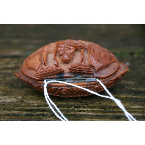 602 - A Georgian coquilla nut snuff box deeply carved with a figural scene depicting a woman holding a bab... 