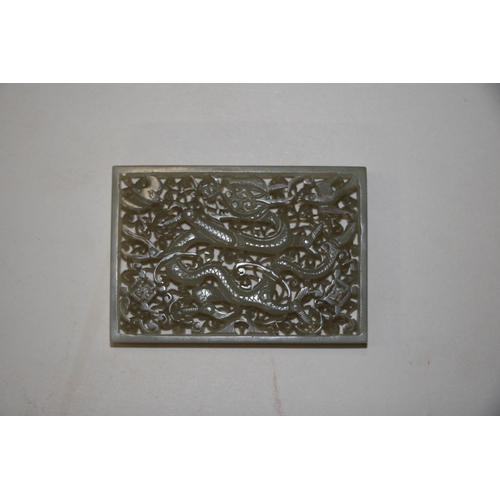 463 - A Chinese pierced rectangular jade plaque depicting a dragon, birds and bats amongst foliage, on a h... 