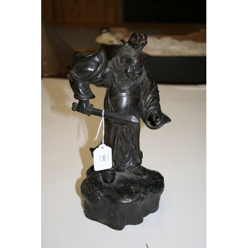 542 - A Japanese bronze figure in the form of a warrior holding a sword, on a rocky base, 33cms (13ins) hi... 