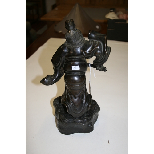 542 - A Japanese bronze figure in the form of a warrior holding a sword, on a rocky base, 33cms (13ins) hi... 