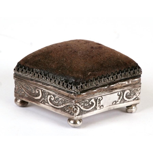 205 - An Edwardian silver pin cushion of rectangular form with repeating wave scroll decoration, on bun fe... 