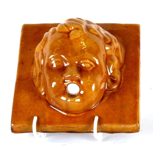 74 - A treacle glazed fountain decorated in relief with a cherub head, 15cms (6ins) wide.