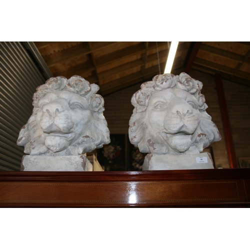 30 - A pair of distressed painted urns in the form of lion heads, each 43cms (17ins) high (2).