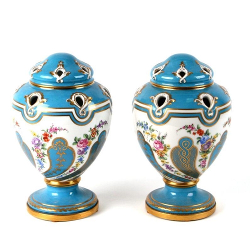 129 - A pair of Sevres style pot pourri vases and covers decorated with sprays of flower within vignettes ... 