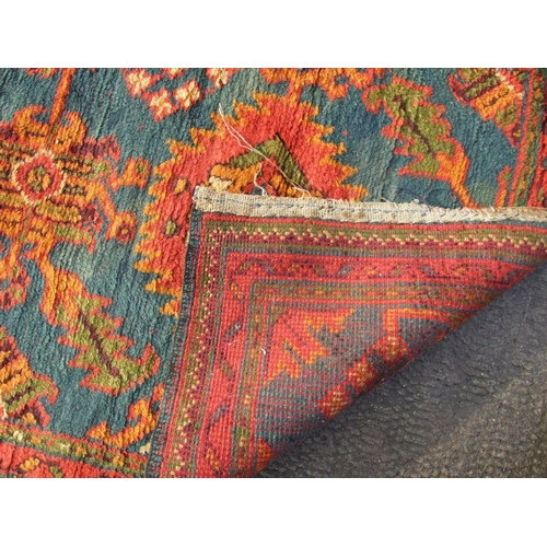 235 - A Turkish hand knotted woollen runner with repeated floral motifs on a blue ground within a multi bo... 